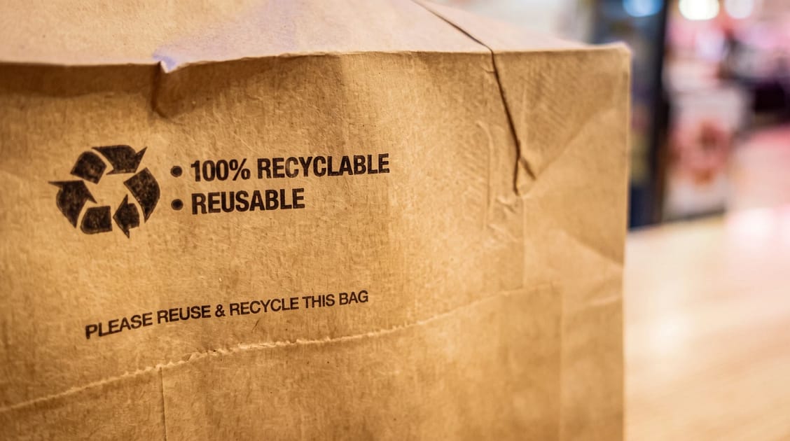 Brown paper bag showing the recycled logo and recycling message