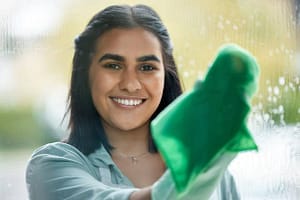 Lady cleaning window with green cloth
