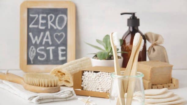 Eco-friendly bamboo toothbrushes in glass container on vanity with several other eco-friendly self care accessories