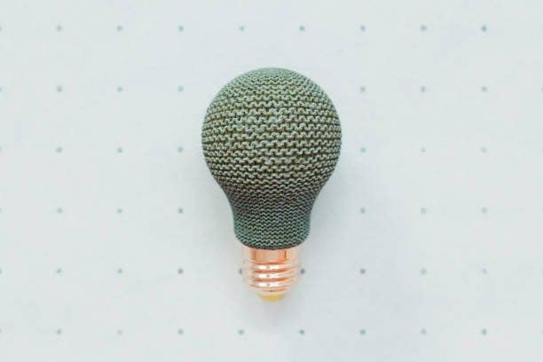 Knitted light bulb against turquoise backdrop with polka dots conceptual 3D illustration