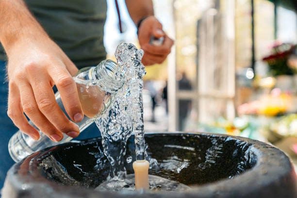 Mid-adult man refilling his reusable water bottle on the drinking fountain in Yerevan in Armenia. Close-up.