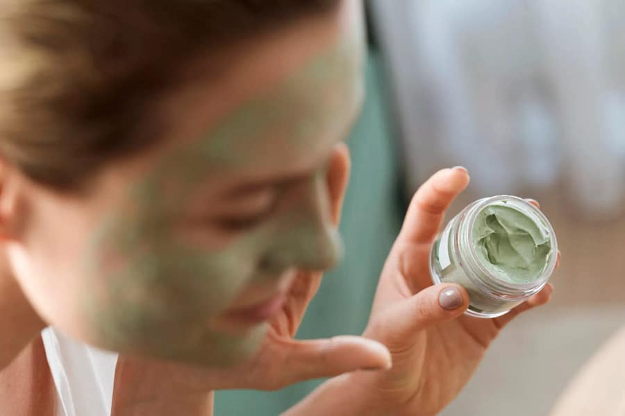 Lady putting hemp seed face mask cream on